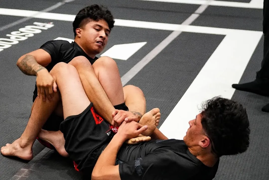 Two grapplers working from the saddle position during No-Gi training at AOE