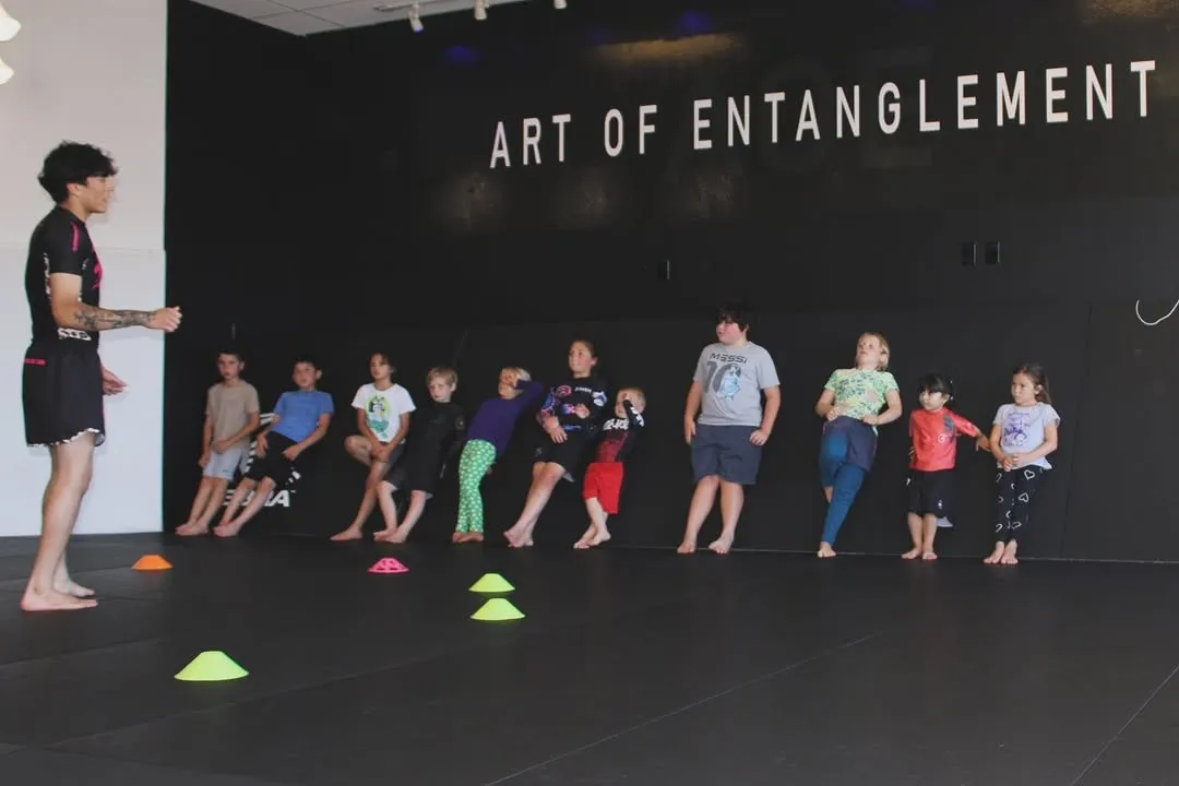 Kids working footwork and pad drills in a youth kickboxing class at AOE in Monterey